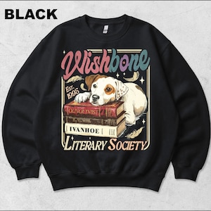 May include: A black crewneck sweatshirt featuring a graphic of a Jack Russell Terrier resting its head on a stack of three books. The text reads Wishbone, Est. 1995, and Literary Society. The books are titled Oliver Twist and Ivanhoe.