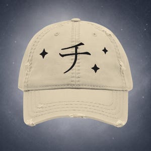 Peut inclure: Casquette de baseball beige vieilli avec un caractère japonais noir et trois formes de diamant noires. La casquette a une visière incurvée et un aspect usé et vintage.