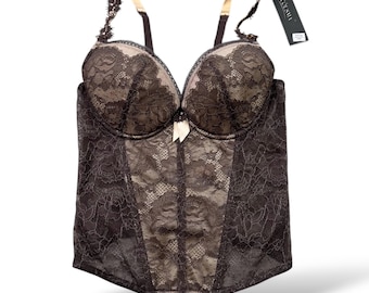 May include: A black lace corset with a beige lining and a small bow. The corset has adjustable straps and a tag that reads "Accusita". The garment is designed with intricate floral lace patterns.