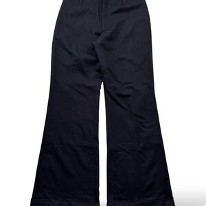 May include: Black flared pants with a classic design. The pants have a high waist and a wide leg that flares out from the knee. The hem is cuffed. The pants are made of a solid, dark fabric.