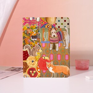 May include: A rectangular tablet case featuring a vibrant collage of autumn-themed illustrations, including a dog in a striped sweater, a fox, a squirrel, a red apple, a small house, and various patterned sections in shades of orange, pink, and yellow.