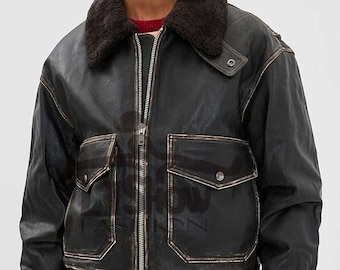 May include: A black leather bomber jacket with a brown shearling collar. The jacket has a zip-up front, two front pockets, and a ribbed hem and cuffs. The jacket is worn over a red sweater and blue jeans.