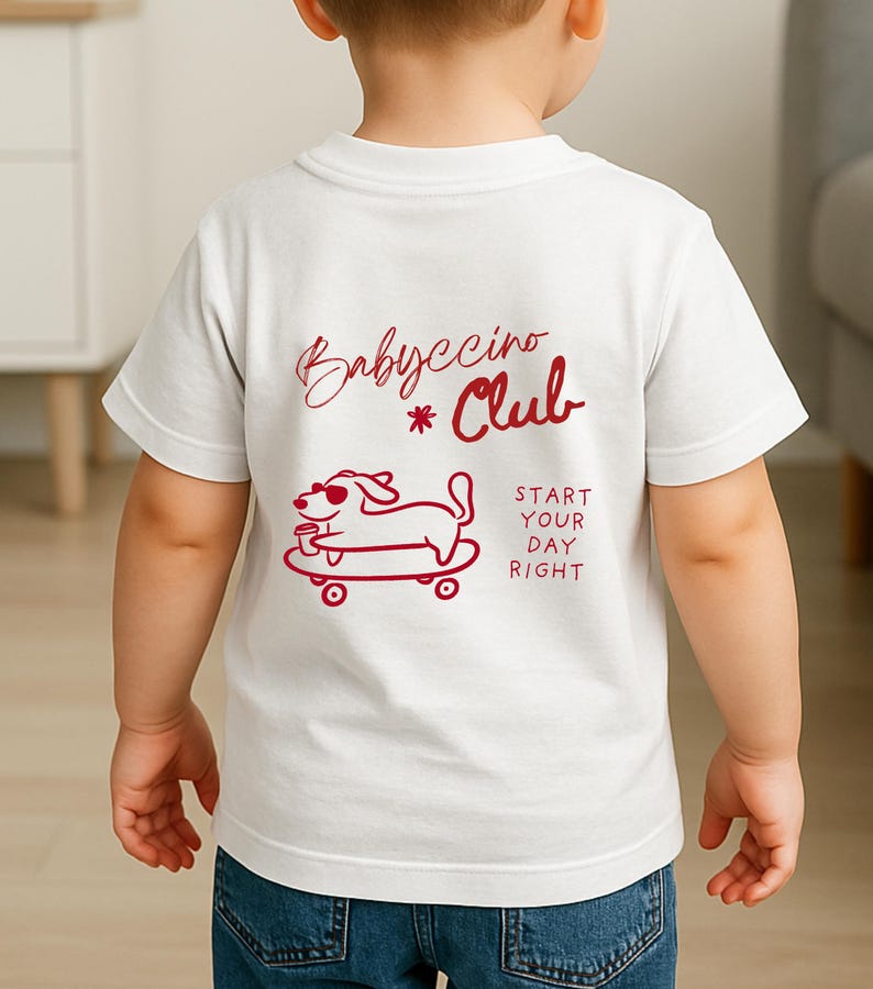 Peut inclure: T-shirt blanc avec un motif rouge au dos. Le motif comprend les mots "Babyccino Club" et un chien de dessin anim&eacute; sur un skateboard tenant une tasse. L'expression "Start Your Day Right" est &eacute;galement imprim&eacute;e sur le t-shirt.