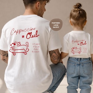 Peut inclure: Deux t-shirts blancs assortis avec des graphiques rouges. L'un affiche "Cappuccino Club" avec un chien sur un skateboard, l'autre "Babyccino Club". Les deux ont le texte "Start Your Day Right".