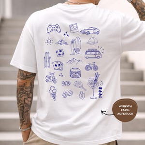 May include: A white short-sleeve t-shirt featuring a blue line-art graphic on the back. The design includes various icons such as a game controller, car, surfboard, van, bicycle, burger, ice cream, dumbbell, and the text DAD and 1998.