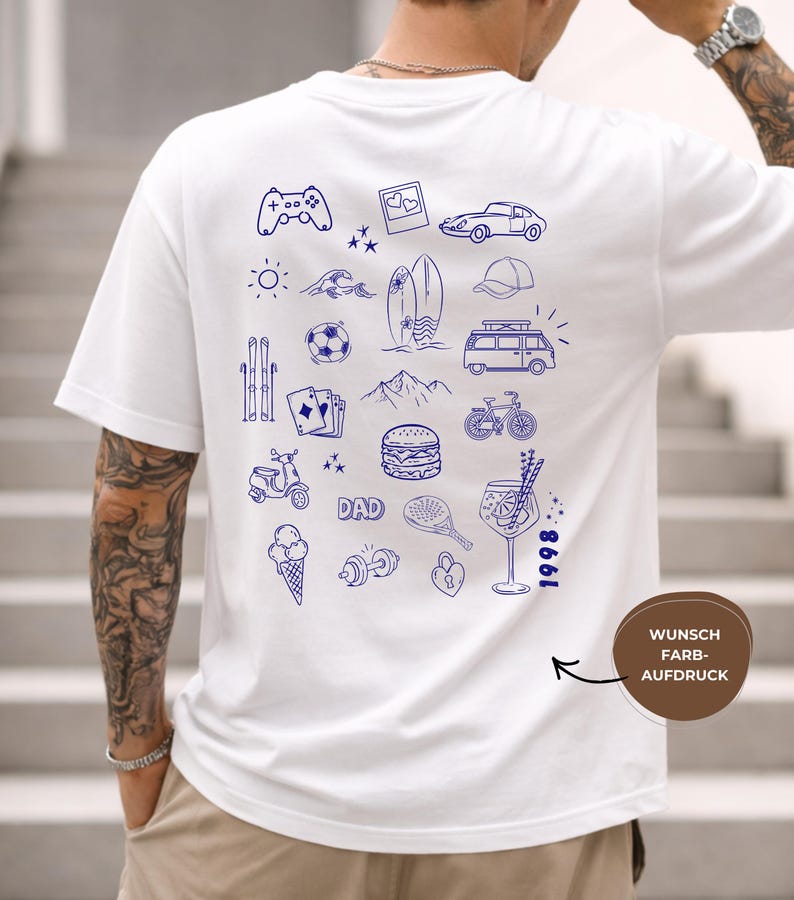 May include: A white short-sleeve t-shirt featuring a blue line-art graphic on the back. The design includes various icons such as a game controller, car, surfboard, van, bicycle, burger, ice cream, dumbbell, and the text DAD and 1998.