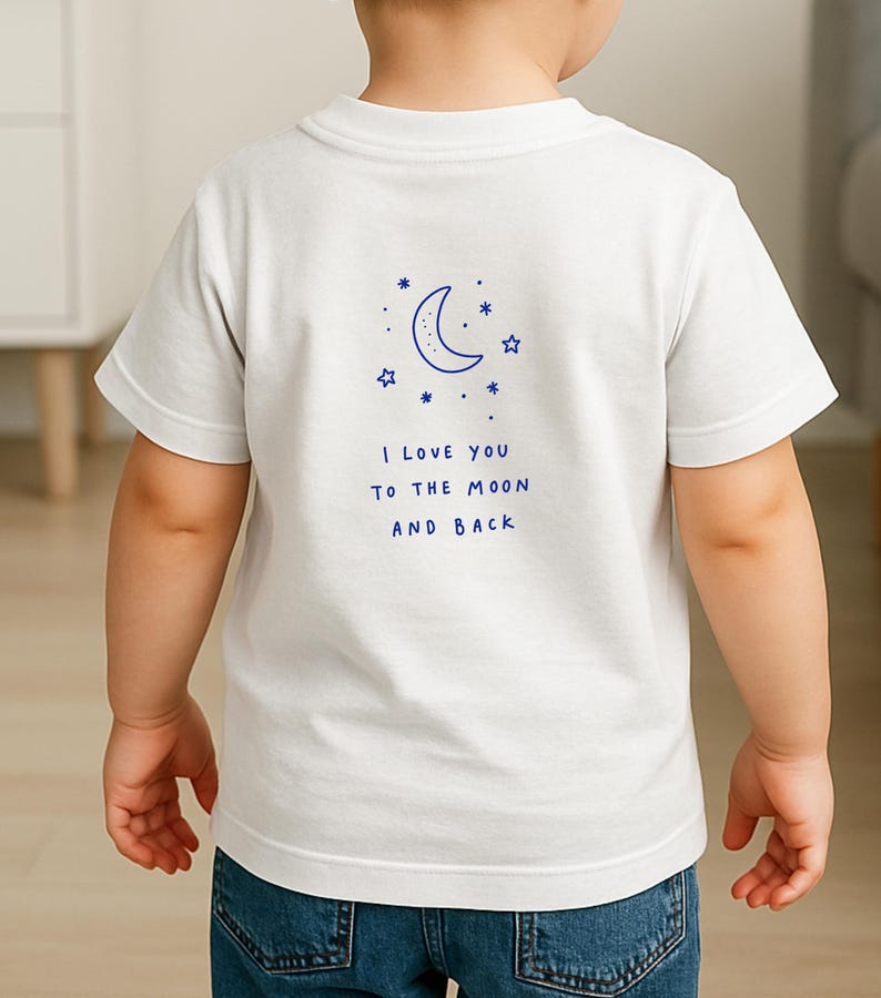 May include: White t-shirt with a blue crescent moon and star design. The text "I LOVE YOU TO THE MOON AND BACK" is printed below the graphic. The shirt is worn by a child.