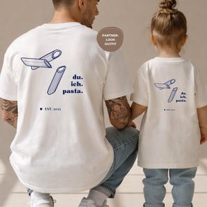 Peut inclure: T-shirts blancs avec un motif de pâtes et le texte "du. ich. pasta." en bleu marine. Les chemises présentent également une illustration de pâtes et le texte "EST. 2023". Les chemises font partie d'une tenue de couple.