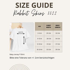 Peut inclure: Un guide des tailles pour les t-shirts en jersey Rabbit Skins pour b&eacute;b&eacute;s. Il indique les mesures de la largeur de la poitrine et de la longueur du corps en centim&egrave;tres, de 3-6 mois &agrave; 18-24 mois. Le texte inclut "WEITE" et "L&Auml;NGE".