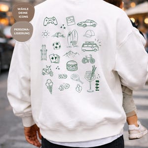 Könnte beinhalten: Ein weißes Sweatshirt mit Rundhalsausschnitt und einer Ansammlung dunkelgrüner Strichzeichnungen auf der Rückseite, darunter ein Gamecontroller, Auto, Surfbrett, Van, Fahrrad, Burger, Eis, Cocktail sowie der Text DAD und 1998.