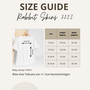 May include: A size guide for Rabbit Skins baby jersey t-shirts. The guide shows chest width and body length measurements in centimeters for sizes 3-6 months to 18-24 months. The text also includes the phrase "Bitte eine Toleranz von +/- 2cm ber&uuml;cksichtigen."
