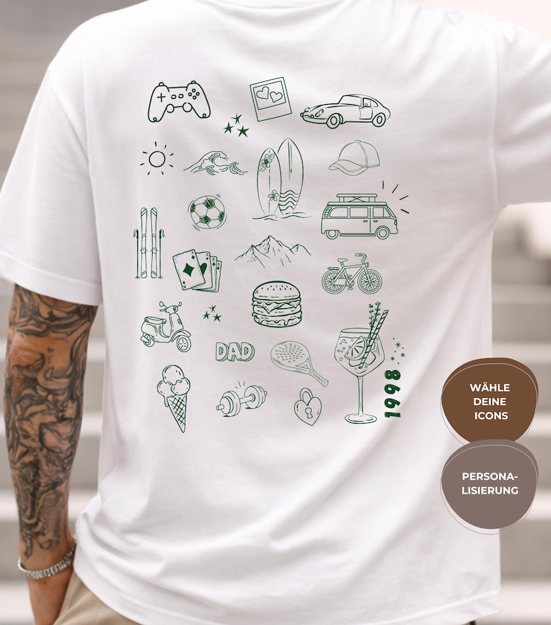 May include: A white t-shirt featuring a dark green line art graphic on the back. The design includes various icons such as a game controller, car, surfboard, van, bicycle, scooter, burger, cocktail, and the text DAD and 1998. The shirt is plain white.