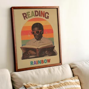 May include: A framed print with a retro design featuring a person wearing sunglasses and reading a book. The text "READING RAINBOW" is below the image.