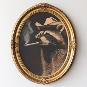 May include: Oval gold framed art print featuring a raccoon wearing a cowboy hat and smoking a cigarette. The raccoon is depicted with detailed fur and a serious expression. The background is dark, contrasting with the gold frame.