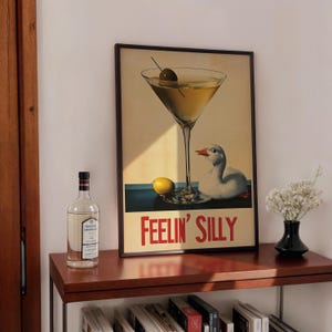 Puede incluir: Un p&oacute;ster vintage enmarcado con una copa de martini y un ganso. El p&oacute;ster tiene el texto "Feelin' Silly" en letras rojas.