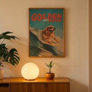 May include: A framed poster with the words "GOLDEN HOUR" in red letters, featuring a dog wearing sunglasses surfing a wave. The poster is displayed above a wooden cabinet with a round, glowing lamp and a potted plant.