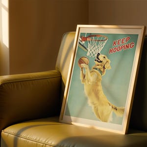 May include: A framed print featuring a golden retriever playing basketball. The dog is jumping to shoot a basketball into a hoop. The print has a light blue background and the words "KEEP HOOPING" in red.