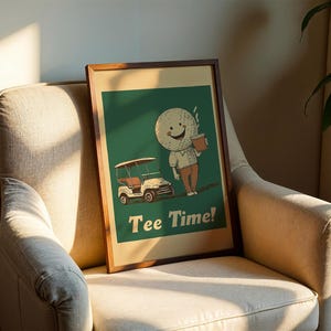 May include: A framed print with a green background featuring a cartoon golf ball character holding a cup of coffee and a golf cart. The text "Tee Time!" is printed below the character.