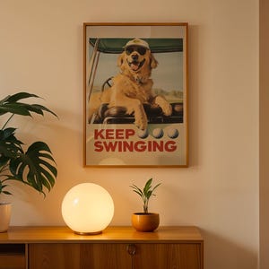 May include: A framed poster with a golden retriever wearing a golf cap and sunglasses, sitting in a golf cart. The poster has the text "Keep Swinging" in red and white letters.