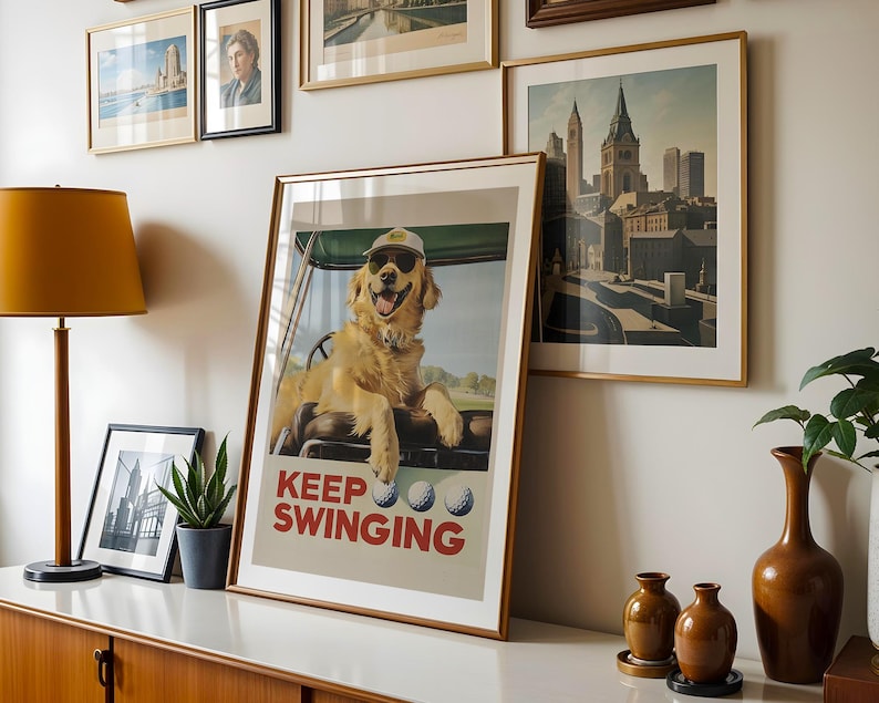 May include: A poster with a golden retriever dog wearing a golf hat and sitting in a golf cart. The poster has the text "Keep Swinging" and three golf balls.