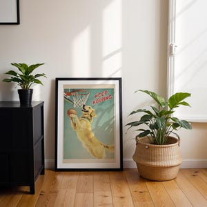 May include: A framed poster with a black border features a golden retriever dog dunking a basketball. The poster has the words "KEEP HOOPING" in red. The room has a black cabinet, a wicker basket with a plant, and a potted plant.
