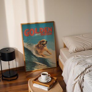 May include: A framed poster with a surfing golden retriever wearing sunglasses, the words "GOLDEN HOUR" in red, and a blue and white background. A black lamp, a wooden tray with a coffee cup, and a bed with beige bedding are also visible.