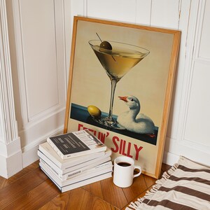 Puede incluir: Un p&oacute;ster vintage enmarcado con una copa de martini y un pato. El p&oacute;ster tiene el texto "Gettin' Silly" en letras rojas y blancas.
