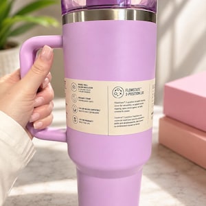 May include: A lavender insulated travel mug with a handle and a 3-position lid. The mug features double-wall vacuum insulation and is dishwasher safe. The text on the mug reads "FLOWSTATE 3-POSITION LID".