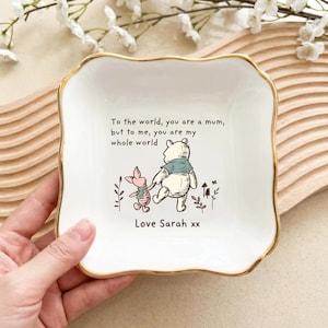 Könnte beinhalten: Eine weiße Keramik-Schmuckschale mit goldenem Rand, mit einer Illustration von Winnie Puuh und Ferkel. Die Schale trägt den Text "To the world, you are a mum, but to me, you are my whole world. Love Sarah xx."