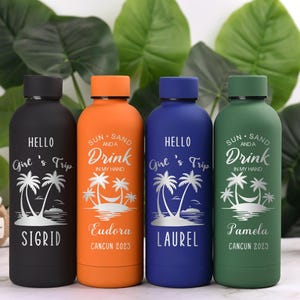 May include: Four insulated water bottles in black, orange, blue, and green. Each bottle has a black lid and features a tropical design with text. The text includes names and the phrase "Girl's Trip" or "Sun, Sand, and a Drink."