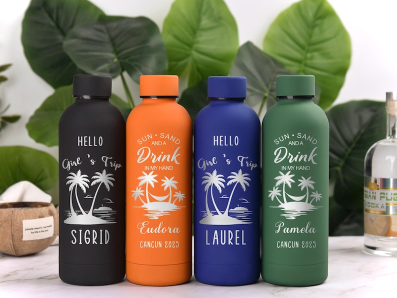May include: Four insulated water bottles in black, orange, blue, and green. Each bottle has a black lid and features a tropical design with text. The text includes names and the phrase "Girl's Trip" or "Sun, Sand, and a Drink."