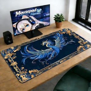 以下が含まれることがあります： 青いフェニックスのデザインと金色のアクセントが施された長方形のマウスパッド。マウスパッドは、フェニックスの詳細なイラストが描かれた濃い青色の背景です。ボーダーには金色の花柄が施されています。コンピューターモニターには「Mousepad Haven」というテキストが表示されています。