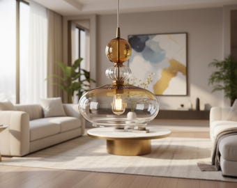 May include: A pendant light fixture featuring a tiered design with a clear glass base, a ribbed glass middle section, and a smooth amber glass sphere at the top. The fixture is suspended by a thin cord and includes a visible internal light bulb.