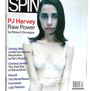 May include: A magazine cover featuring the text "SPIN" at the top. The cover story is "PJ Harvey Raw Power." The image shows a person with dark hair and a white bra. Additional text includes article titles and a barcode.