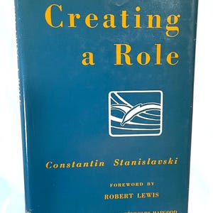 May include: A hardcover book titled "Creating a Role" by Constantin Stanislavski. The cover is a deep teal with gold lettering and a white and black graphic. The foreword is by Robert Lewis.
