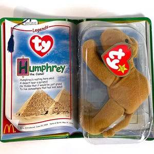Pu&ograve; includere: Un giocattolo a forma di cammello Ty Beanie Baby, Humphrey, nella sua confezione originale. La confezione &egrave; progettata per assomigliare a un libro, con il nome del cammello e una poesia stampata sulla pagina sinistra. Il cammello &egrave; marrone chiaro con un'etichetta rossa a forma di cuore.