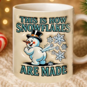 May include: A cream-coloured ceramic mug featuring a snowman graphic and the text "THIS IS HOW SNOWFLAKES ARE MADE." Available in 312 ml and 425 ml sizes. The snowman wears a black top hat and has a carrot nose.
