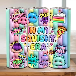 Könnte beinhalten: Ein zylindrischer Becher mit pastellfarbenem Streifenhintergrund und 3D-Grafiken von Zeichentrickfiguren, einem Stück Kuchen, einem Stück Pizza sowie dem Text "SQUISH!", "SOFT!", "SQUEEZE", "FUN!", "POP!", "IN MY SQUISHY ERA" und "GOOD VIBES!"