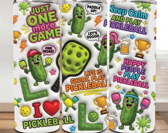 May include: Three white stainless steel tumblers with pickleball-themed graphics. The designs include cartoon pickles, pickleball paddles, and phrases like "Just One More Game" and "Keep Calm and Play Pickleball." The tumblers are decorated with bright colors.