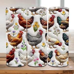 May include: Three white insulated tumblers with a repeating pattern of colorful chickens, flowers, and foliage. The chickens are depicted in various colors and poses against a white background. The tumblers are displayed on a wooden surface.
