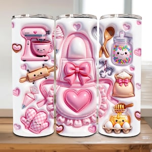 Puede incluir: Un vaso blanco con un tema de repostería rosa. El diseño incluye una batidora rosa, un rodillo, un delantal y otros gráficos relacionados con la repostería. Corazones y cupcakes rosas están dispersos alrededor del diseño. El vaso es de unos 590 ml.