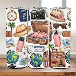 Pode incluir: Um copo branco com tema de viagem com ilustrações de bússola, passaporte, câmera, mala, chapéu, óculos de sol, garrafa de água, globo, avião e cartão de embarque. O design inclui uma cena de praia e bandeiras.