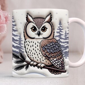 May include: White ceramic mug featuring a detailed illustration of a brown and white owl perched on a snowy branch. The owl has large, expressive eyes and is set against a backdrop of snow-covered pine trees. The mug has a white handle.