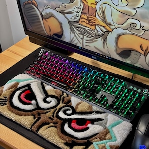 Peut inclure: Un clavier mécanique MSI noir avec éclairage RVB est posé sur un tapis de souris noir, à côté d'une souris assortie. Un tapis personnalisé avec un motif de visage de tigre de dessin animé est sur le tapis. Un écran d'ordinateur affiche un personnage de dessin animé.