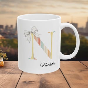 Caneca personalizada com a letra N, caneca com inicial personalizada, caneca de café com laço em tons pastel, caneca com nome feminino, caneca com monograma para presente.