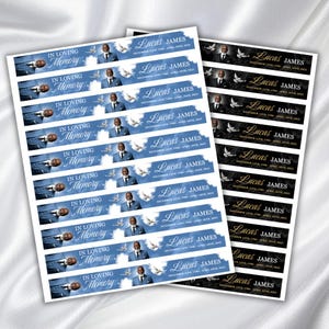 Puede incluir: Hojas de pegatinas conmemorativas con el texto "IN LOVING MEMORY" y "Lucas James" impreso. Las pegatinas presentan un retrato de un hombre, palomas y fechas sobre un fondo azul y negro.