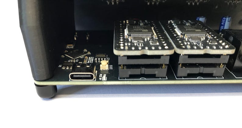 K&ouml;nnte beinhalten: Nahaufnahme eines schwarzen elektronischen Ger&auml;ts mit einem USB-C-Anschluss und zwei Leiterplatten. Die Leiterplatten sind gestapelt und haben mehrere kleine Komponenten. Das Ger&auml;t befindet sich auf einer wei&szlig;en Oberfl&auml;che.