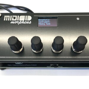 K&ouml;nnte beinhalten: Schwarzer elektronischer Musiksynthesizer mit dem Text "MIDIGID morpheus" und einem kleinen Bildschirm, der Optionen anzeigt. Er hat vier schwarze Kn&ouml;pfe und eine silberne Zierleiste. Ein Kabel ist oben links angeschlossen.