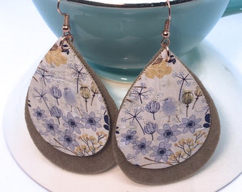 May include: A pair of teardrop-shaped earrings with a floral pattern on a white background. The earrings are made of cork and have a brown felt backing.
