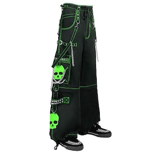 May include: Black cargo pants with neon green stitching and accents. Features include skull patches, chains, and studded straps. The pants have multiple pockets and a drawstring waist, showcasing a punk or alternative style.